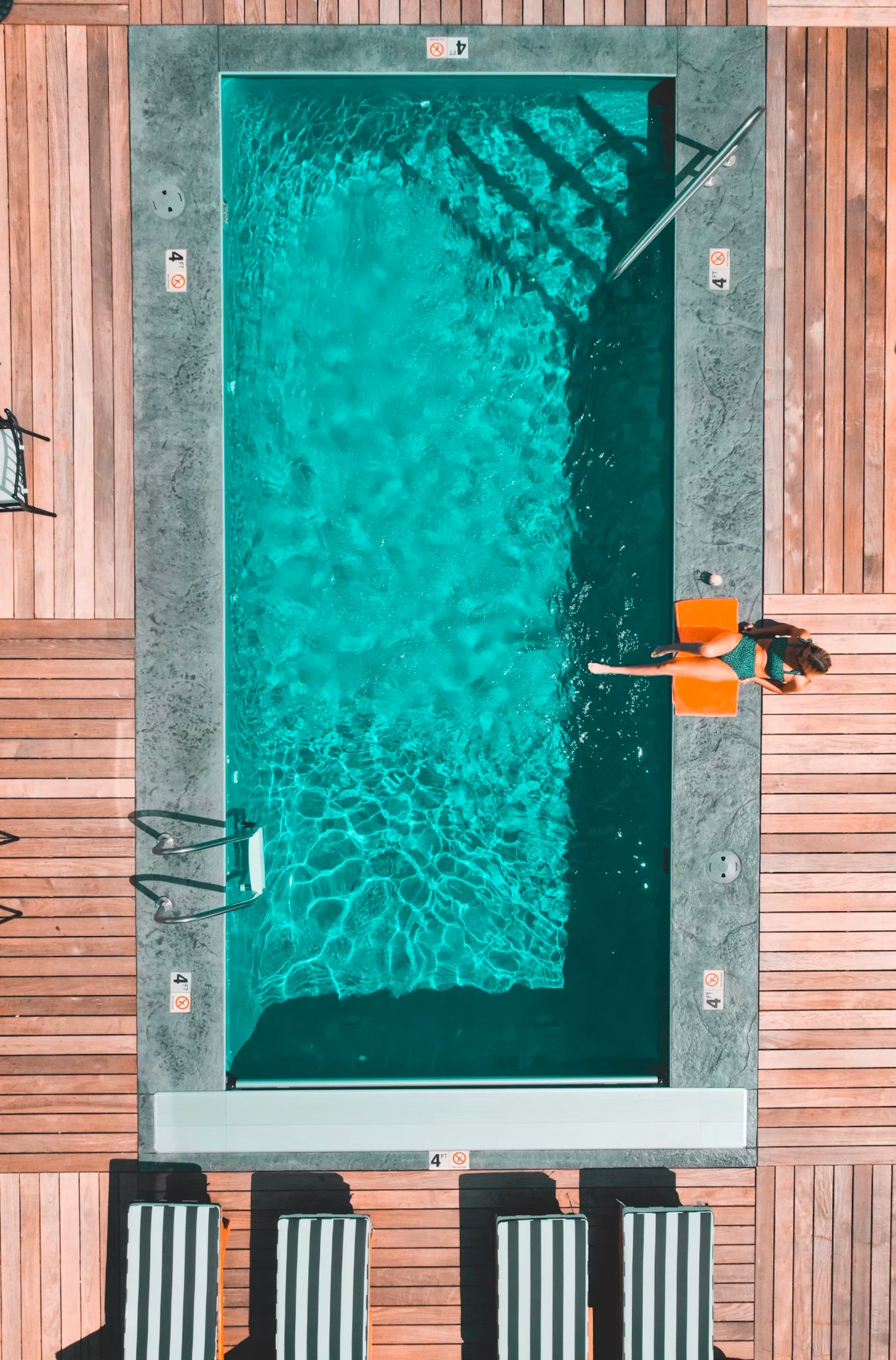 Piscina vista desde arriba con el agua transparente y escalera de acero